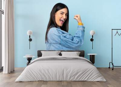 Young caucasian woman isolated on blue background celebrating a victory Wall mural