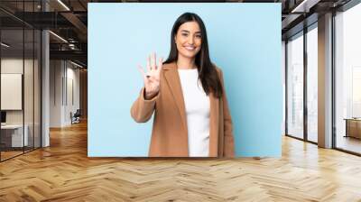 Young caucasian woman isolated on blue background happy and counting four with fingers Wall mural