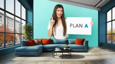 Young caucasian woman isolated on blue background holding a placard with the message PLAN A and thinking Wall mural