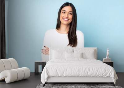 Young caucasian woman isolated on blue background keeping the arms crossed in frontal position Wall mural