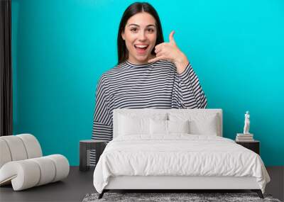 Young caucasian woman isolated on blue background making phone gesture. Call me back sign Wall mural