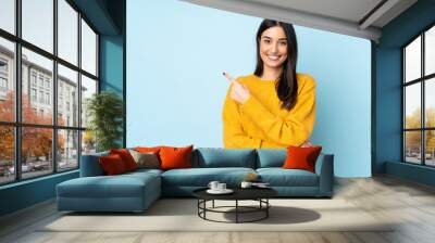 Young caucasian woman isolated on blue background pointing to the side to present a product Wall mural