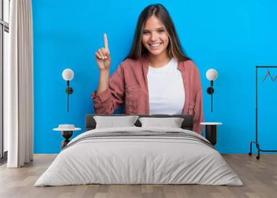 Young caucasian woman isolated on blue background pointing up a great idea Wall mural