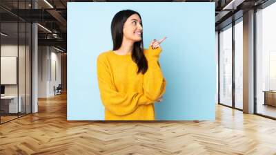 Young caucasian woman isolated on blue background pointing up a great idea Wall mural