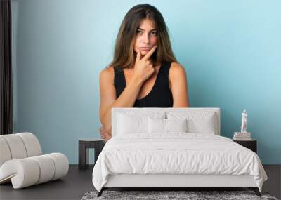 Young caucasian woman isolated on blue background thinking Wall mural