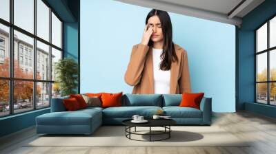 Young caucasian woman isolated on blue background with headache Wall mural