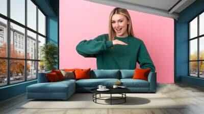 Young caucasian woman isolated on pink background holding copyspace imaginary on the palm to insert an ad Wall mural