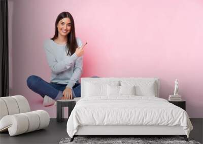 Young caucasian woman isolated on pink background pointing to the side to present a product Wall mural