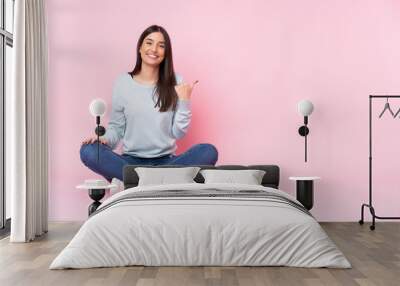 Young caucasian woman isolated on pink background pointing to the side to present a product Wall mural