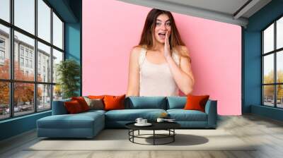 Young caucasian woman isolated on pink background with surprise and shocked facial expression Wall mural