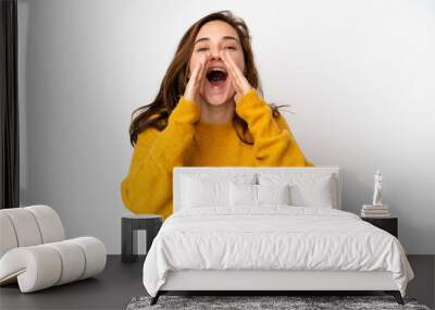 Young caucasian woman isolated on white background shouting and announcing something Wall mural