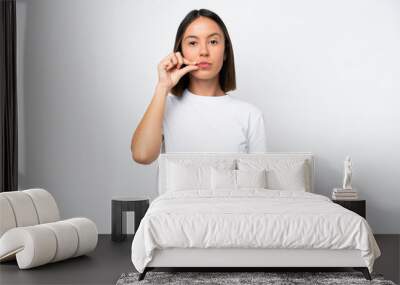 Young caucasian woman isolated on white background showing a sign of silence gesture Wall mural