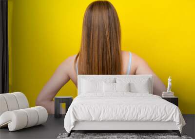 Young caucasian woman isolated on yellow background in back position Wall mural