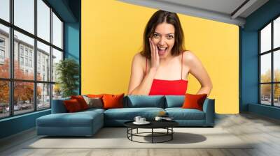 Young caucasian woman isolated on yellow background with surprise and shocked facial expression Wall mural