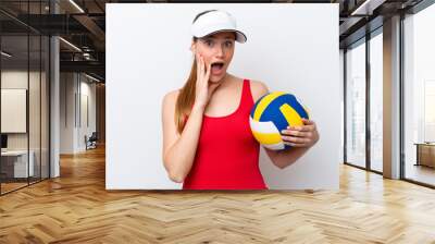 Young caucasian woman playing volleyball isolated on white background with surprise and shocked facial expression Wall mural