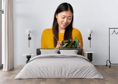 Young Chinese girl over isolated white  background holding a bowl of salad with happy expression Wall mural