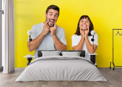 Young couple isolated on yellow background smiling with a happy and pleasant expression Wall mural