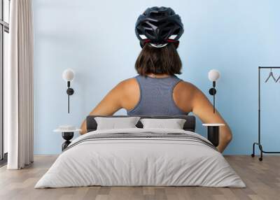 Young cyclist woman isolated on blue background in back position Wall mural