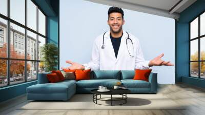 Young doctor man over isolated blue wall with shocked facial expression Wall mural