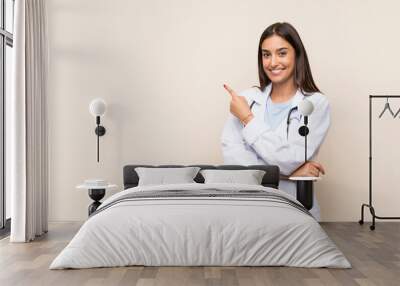 Young doctor woman over isolated background pointing finger to the side Wall mural