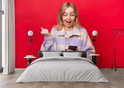 Young English woman isolated on red background surprised and sending a message Wall mural