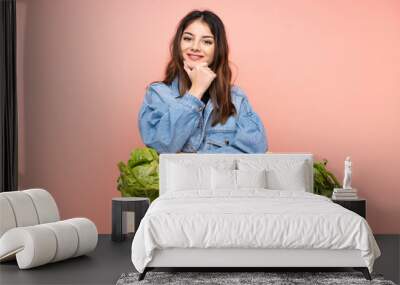 Young farmer woman holding a basket full of fresh vegetables laughing Wall mural