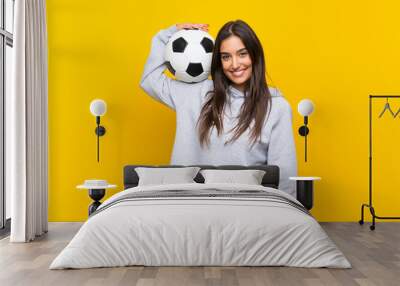 Young football player woman over isolated yellow background Wall mural