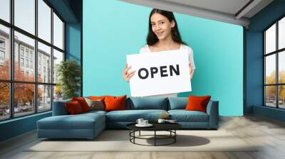 Young French woman isolated on blue background holding a placard with text OPEN with happy expression Wall mural