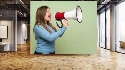 Young girl over green wall shouting through a megaphone Wall mural