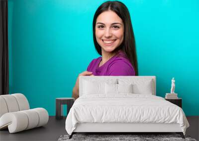 Young girl with band-aids isolated on blue background and pointing it Wall mural