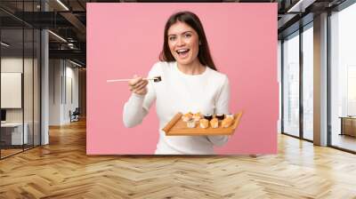 Young girl with sushi over isolated pink background Wall mural