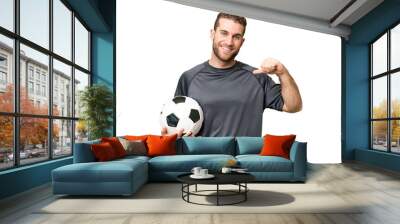 Young handsome blonde man over isolated chroma key background with soccer ball and proud of himself Wall mural