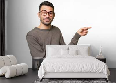 Young handsome caucasian man over isolated background pointing finger to the side Wall mural