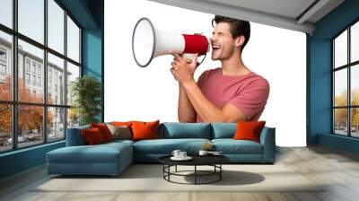 Young handsome caucasian man over isolated background shouting through a megaphone Wall mural