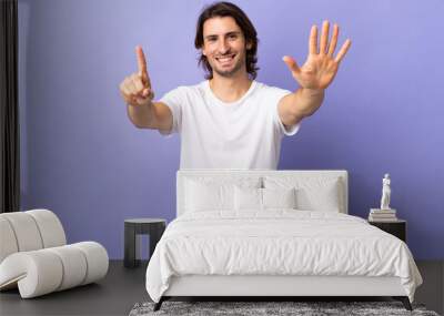 Young handsome man isolated on purple background counting six with fingers Wall mural