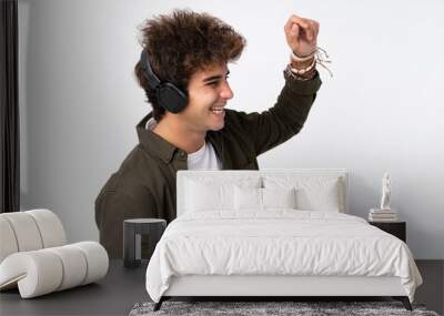 Young handsome man listening music over isolated white wall Wall mural