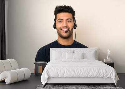 Young handsome man over isolated background working with headset Wall mural