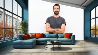 Young handsome man over isolated white background keeping the arms crossed in frontal position Wall mural