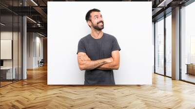 Young handsome man over isolated white background looking up while smiling Wall mural