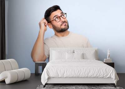 Young handsome man with beard over isolated blue background having doubts and with confuse face expression Wall mural