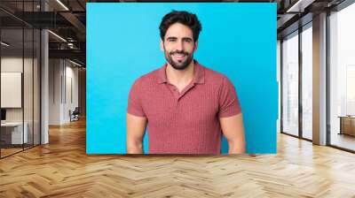 Young handsome man with beard over isolated blue background laughing Wall mural