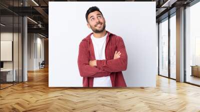 Young handsome man with beard wearing a corduroy jacket over isolated white background looking up while smiling Wall mural