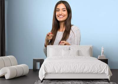 Young hispanic brunette woman pointing to the front and smiling over isolated background Wall mural