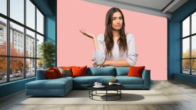 Young hispanic brunette woman unhappy for not understand something over isolated background Wall mural