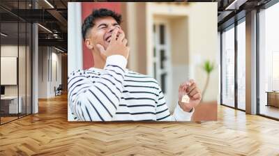 Young hispanic man at outdoors holding home keys with happy expression Wall mural