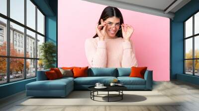 Young Italian woman isolated on pink background With glasses with happy expression Wall mural