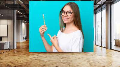 Young Lithuanian woman brushing teeth over isolated background and pointing it Wall mural