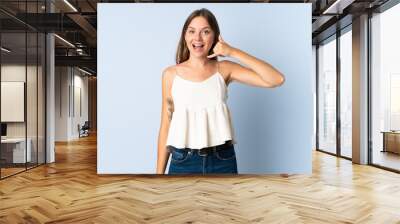 Young Lithuanian woman isolated on blue background making phone gesture. Call me back sign Wall mural