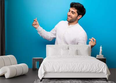 Young man over isolated blue wall enjoy dancing while listening to music at a party Wall mural