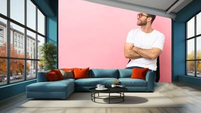 Young man sitting on a chair over isolated pink background in lateral position Wall mural